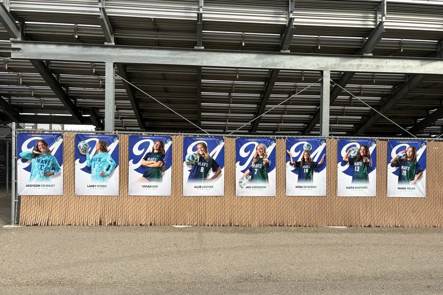 all eight 2026 Mountain View girls soccer senior banners hanging on the fence under the stadium bleachers Meridian Idaho