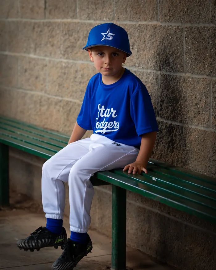 Star Dodgers youth baseball player seated on the dugout bench, Star Idaho