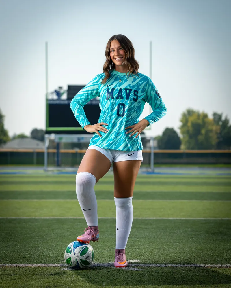 Addyson Crumley #0 full length again, foot on the ball, with the scoreboard and goalposts behind her