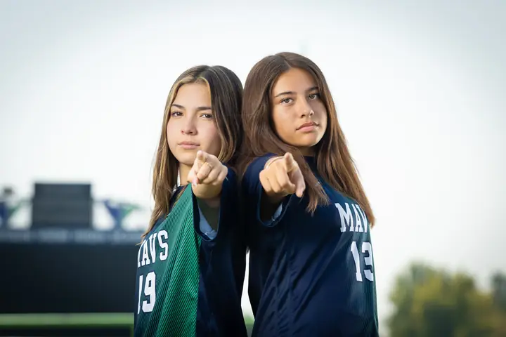 Maria Rojas #19 and Alexa Martinez #13 back to back, pointing at the camera with game faces