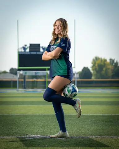 Allie Louvier #8 full length, arms crossed, balancing the ball on her raised knee