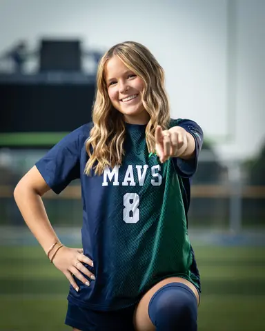 Allie Louvier #8 waist up, smiling and pointing at the camera with a hand on her hip