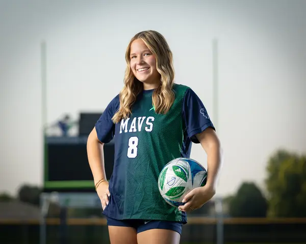 Allie Louvier #8 in a horizontal frame, smiling with the ball at her hip and a hand on her hip