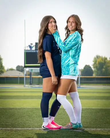 Vivian Sipe #9 and Laney Otero #1, Laney cupping Vivian's cheek on the field