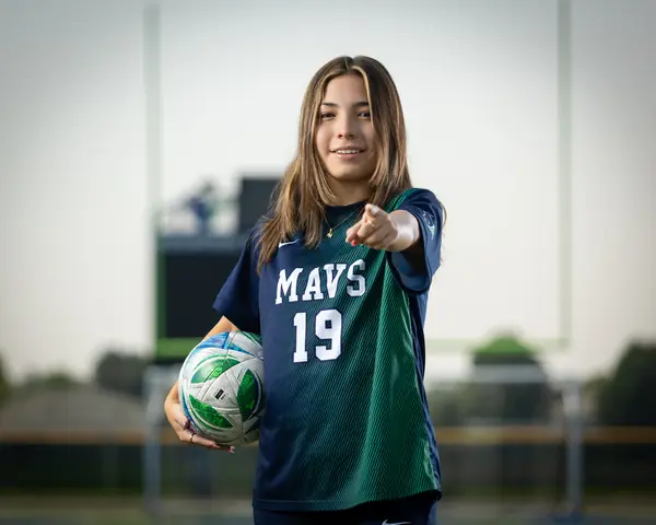 Maria Rojas #19 pointing at the camera with the ball under her arm
