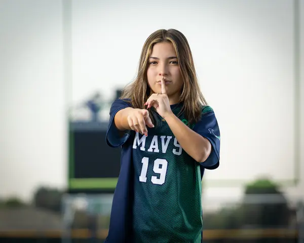 Maria Rojas #19 waist up, finger to her lips, pointing at the camera