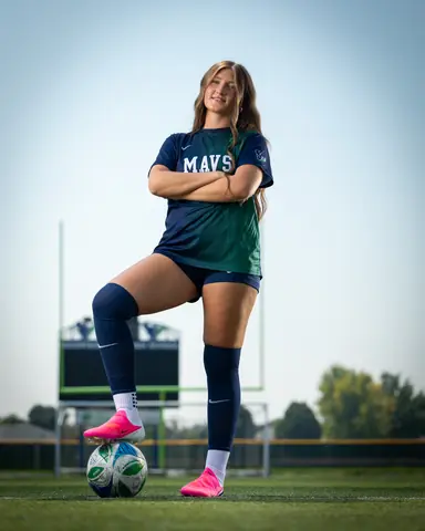 Vivian Sipe #9 full length, arms crossed with one foot on the ball, goalposts behind