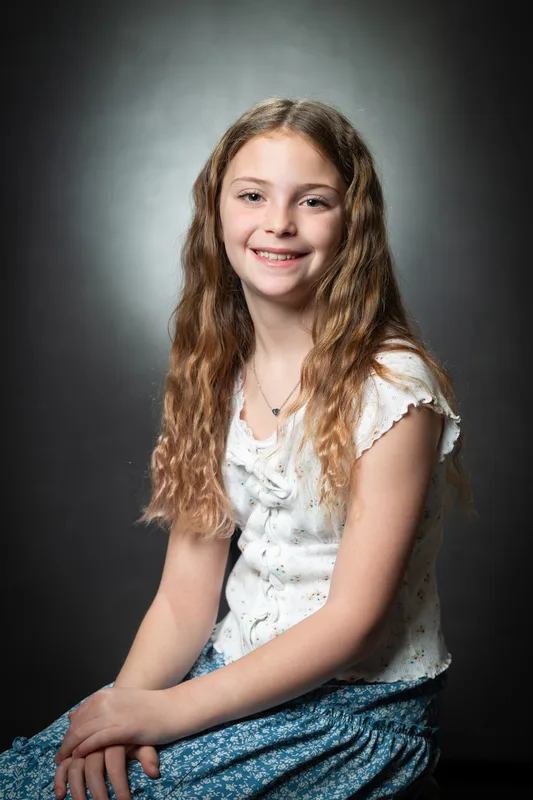 Seated school photo day portrait of a student on a grey studio backdrop with soft spotlight - private school photography Treasure Valley Idaho