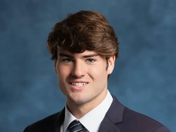 High school male senior in navy suit and striped tie with blue studio background - professional yearbook portrait photography Idaho
