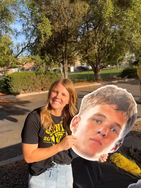 A Bishop Kelly mom smiling with her son's big head cutout outside the stadium