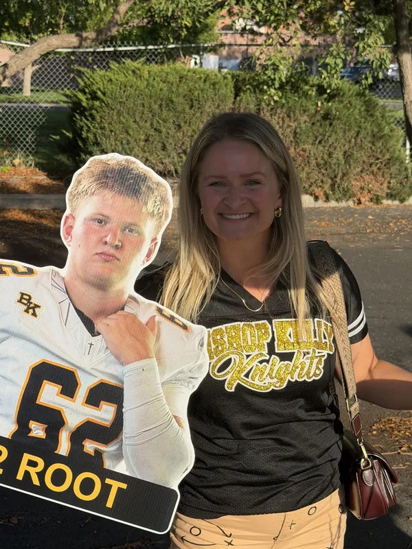 A Bishop Kelly fan posing with a die-cut #62 player sign at a tailgate